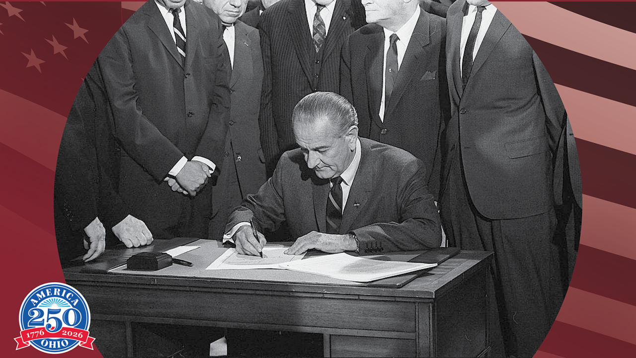 Lyndon B Johnson sitting at a desk signing the Voting Rights Act