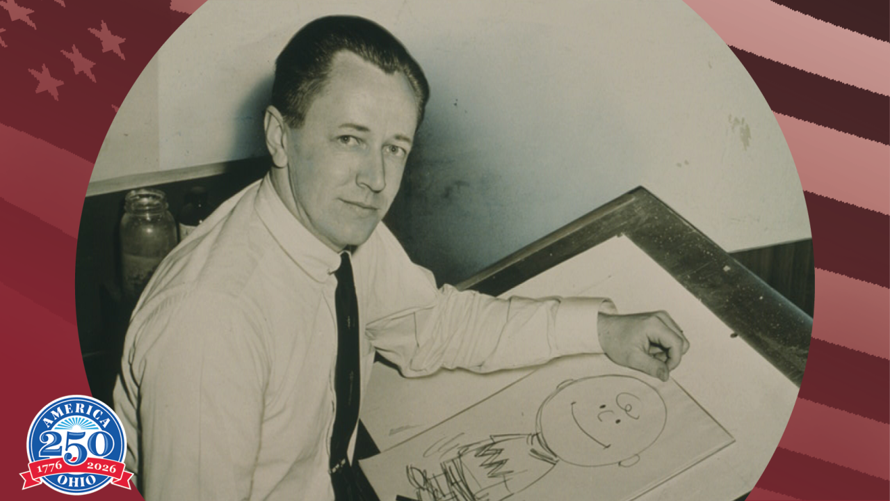 Historic photo of Charles Shultz while he holds an illustration of Charlie Brown