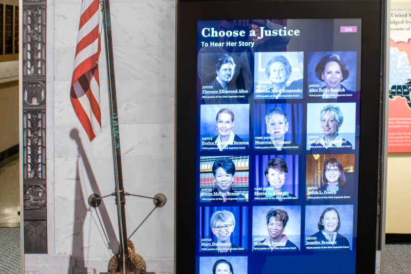 Screen in the Women in Law exhibit displaying pictures of different Justices. The text reads: 