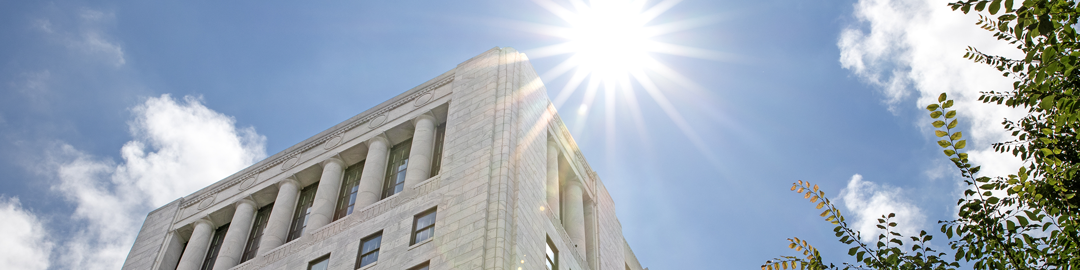 A multi-story, white marble building as seen from the ground looking up.