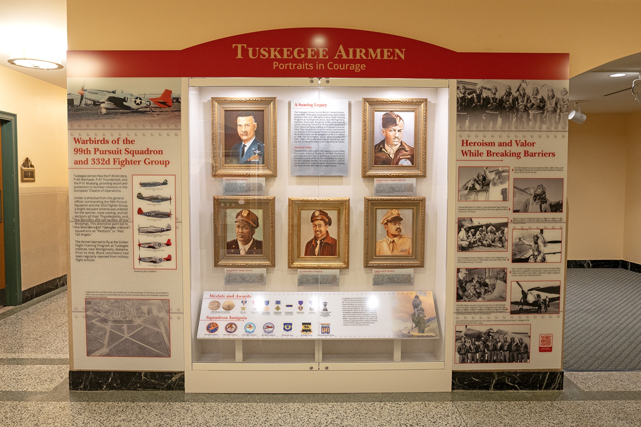 Exhibit featuring five painted portraits of men in military uniforms. To the left of the portraits are images of various military aircraft. To the right of the portraits are several black and white candid photos of military personnel. Below the portraits are images of various military medals.