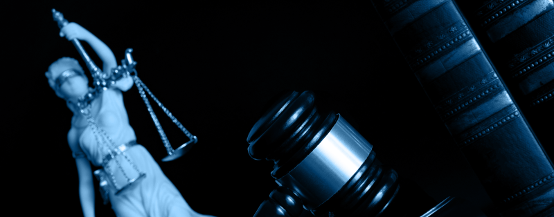 Lady liberty with her scales, a gavel and three large books on a black background