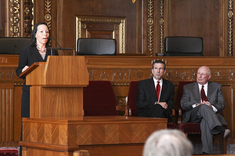 Image of Sharon Davies speaking from behind a podium in the courtroom of the Thomas J. Moyer Ohio Judicial Center.