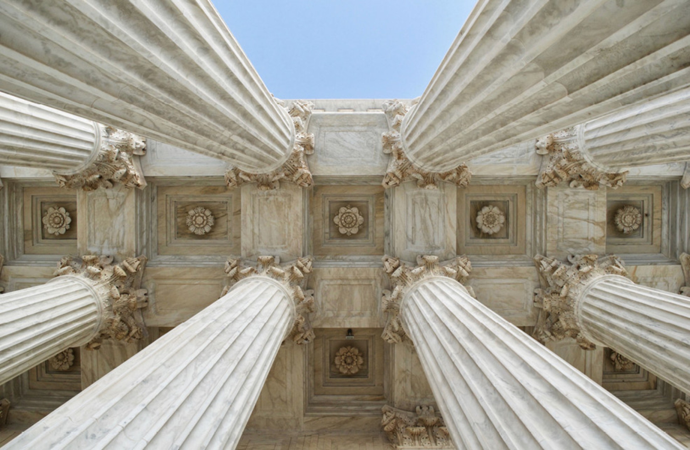 Image of several pillars of a building as seen looking up.