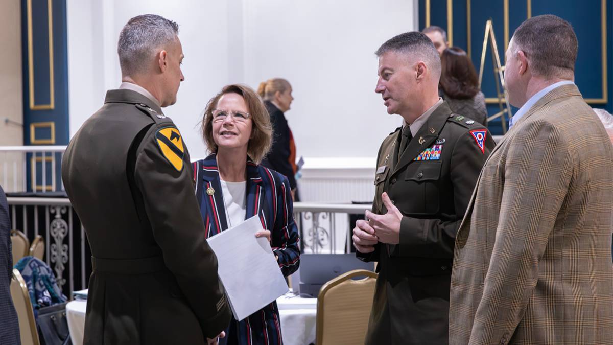 Image of a woman speaking with two men dressed in military uniforms.